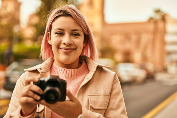 Młoda latynoska dziewczyna uśmiecha się szczęśliwy za pomocą odruchu aparatu fotograficznego w mieście. - Zdjęcie, obraz