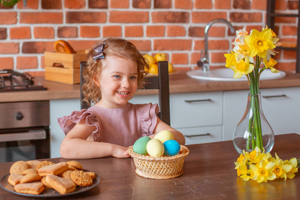 pequena menina bonito com uma cesta de ovos de Páscoa na cozinha em casa - Foto, Imagem