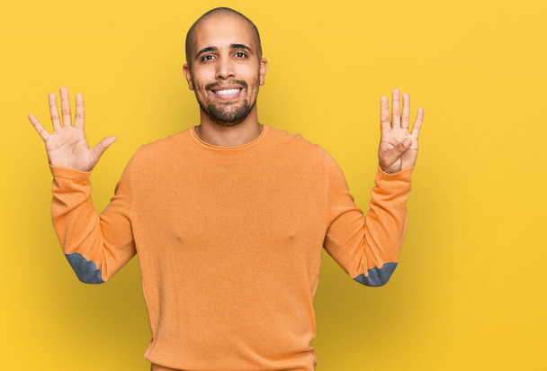 Latino aikuinen mies yllään rento talvi villapaita näyttää ja osoittaa sormilla numero yhdeksän hymyillen itsevarma ja onnellinen.  - Valokuva, kuva