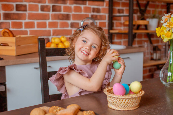 pequena menina bonito com uma cesta de ovos de Páscoa na cozinha em casa - Foto, Imagem