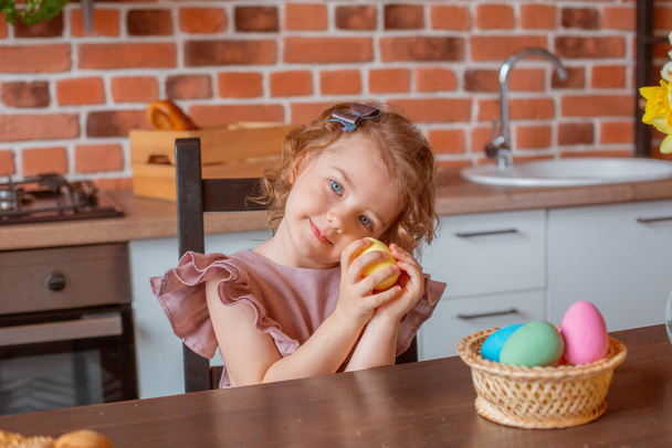 little cute girl with a basket of Easter eggs in the kitchen at home - Foto, Imagem