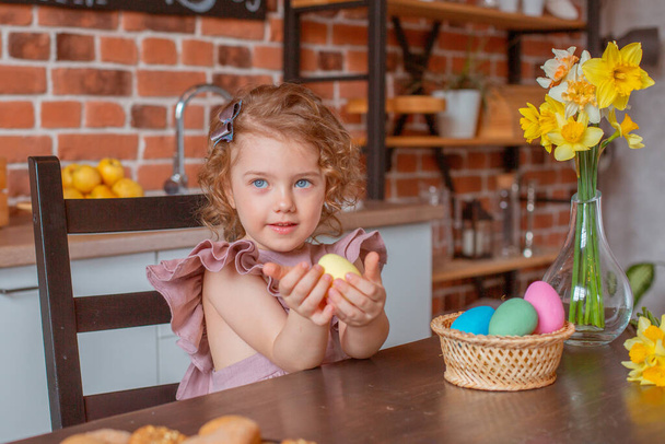 маленька мила дівчинка з кошиком великодніх яєць на кухні вдома
 - Фото, зображення