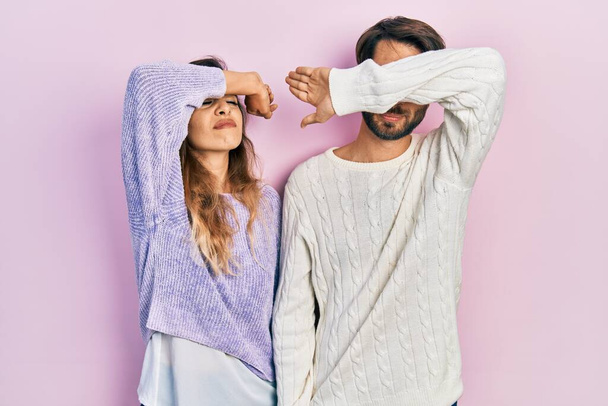 Mladý hispánský pár, oblečený do neformálního oblečení, zakrývajícího oči paží, vypadal vážně a smutně. nevidomý, skrývající a odmítavý koncept  - Fotografie, Obrázek