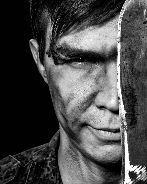 Black white portrait of the soldier in combat coloring, scars and bruises close-up, half of his face is covered with a machete - Φωτογραφία, εικόνα