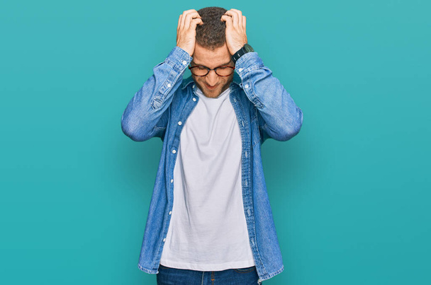 Jeune homme caucasien portant des vêtements décontractés souffrant de maux de tête désespérés et stressés parce que la douleur et la migraine. mains sur la tête.  - Photo, image
