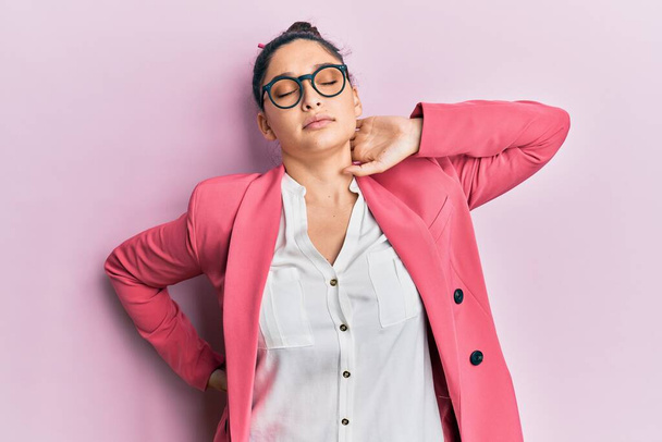 Beautiful middle eastern woman wearing business jacket and glasses suffering of neck ache injury, touching neck with hand, muscular pain  - Fotó, kép