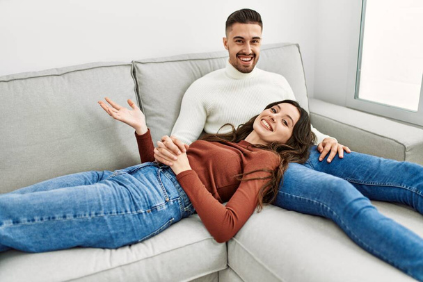 Mladý hispánský pár objímající a odpočívající na pohovce a doma. - Fotografie, Obrázek