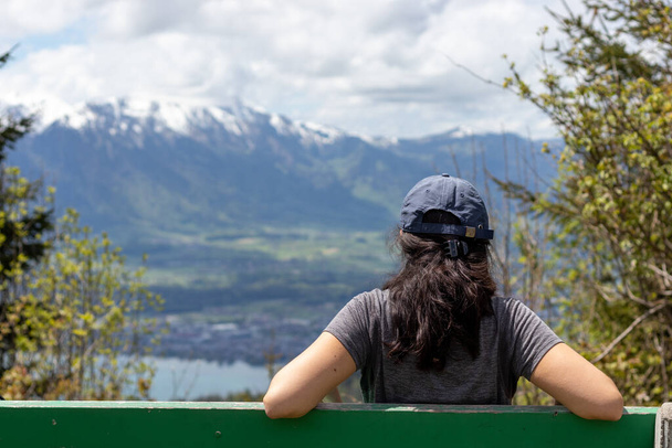 Bankta dinlenen bir kadın, odak dağının manzarasından keyif alıyor. Doğada rahatlama ve yerel seyahat kavramı - Fotoğraf, Görsel