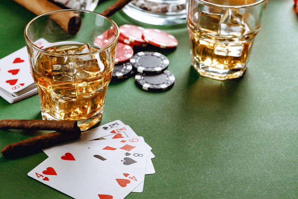 Glass of whiskey, cigar, playing cards and chips on green background - Fotografie, Obrázek