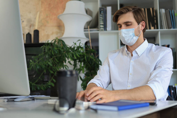 Businessman is working in preventive medical mask in office - 写真・画像