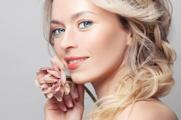 Hermosa mujer con piel limpia, maquillaje natural y flor sobre fondo gris, primer plano retrato - Foto, Imagen