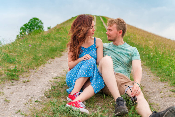 Krásný pár muž a žena sedí na trávě a objímají - Fotografie, Obrázek