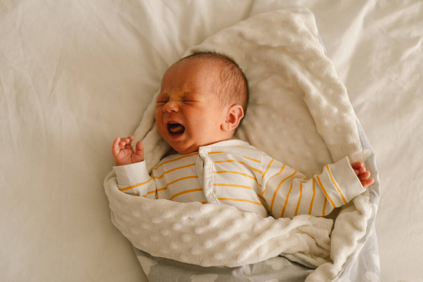 Милий емоційний новонароджений маленький хлопчик плаче в дитячому ліжечку. Пухлинні болі та емоції. немовляти
. - Фото, зображення