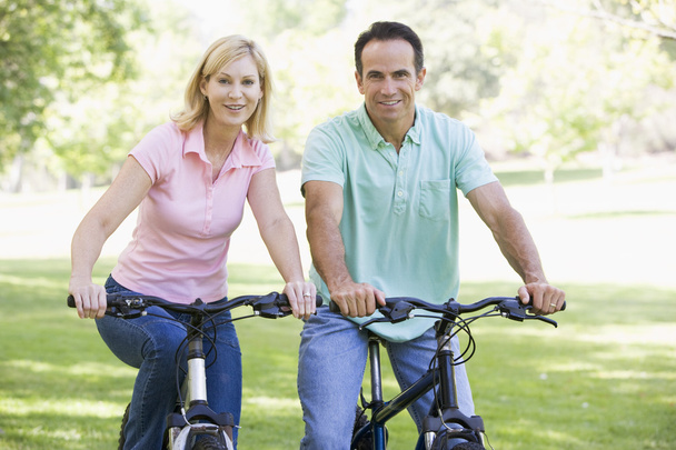 Couple on bikes outdoors smiling - Фото, зображення