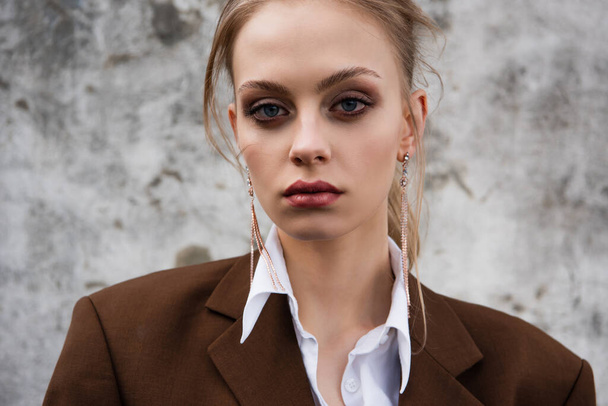 young woman in trendy brown blazer posing near concrete wall - Zdjęcie, obraz