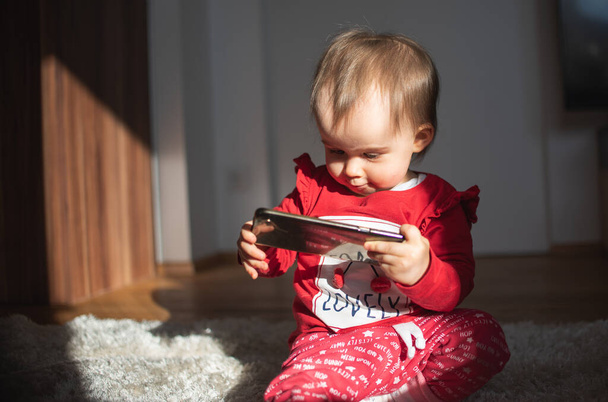 Baby holding smartphone in licht interieur - Foto, afbeelding
