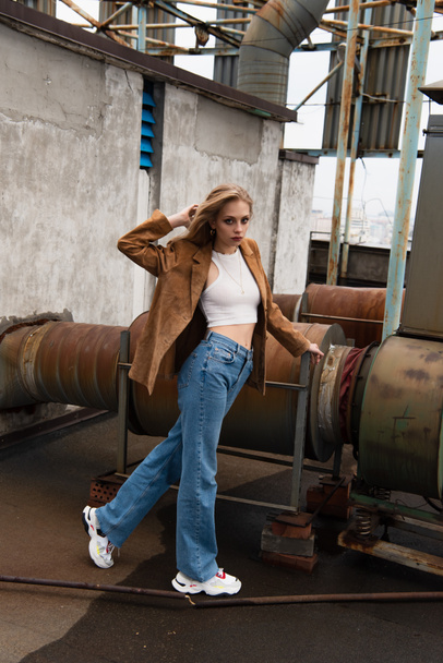 full length of young model in denim jeans and sneakers posing on rooftop - Fotoğraf, Görsel