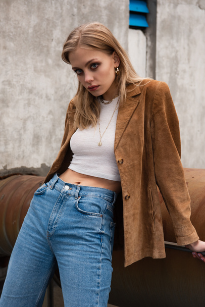 young model in blue jeans and suede blazer posing on rooftop - Foto, Bild