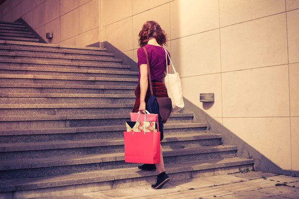 Young woman with shopping walking up stairs - Fotó, kép
