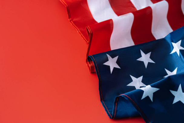 Αμερικανική σημαία διπλωμένη σε κύμα σε κόκκινο φόντο. Έννοια ημέρα ανεξαρτησίας. - Φωτογραφία, εικόνα