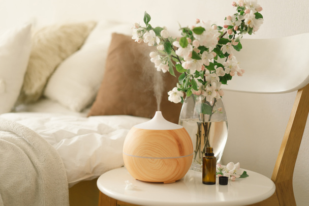 Concepto de aromaterapia. Difusor de aceite de aroma en la silla contra en el dormitorio. Ambientador. Difusor ultrasónico del aroma para el hogar - Foto, imagen