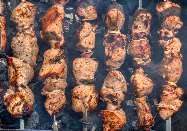 Kebabs prontos brilhantes e frescos em espetos sobre as brasas preparadas em
 - Foto, Imagem