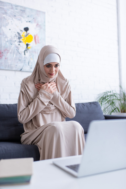 muslim woman showing gratitude gesture during video call on laptop - Photo, Image