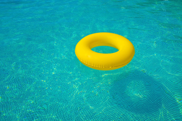 Kleurrijke opblaasbare buis drijvend in een zwembad, zomervakantie concept - Foto, afbeelding