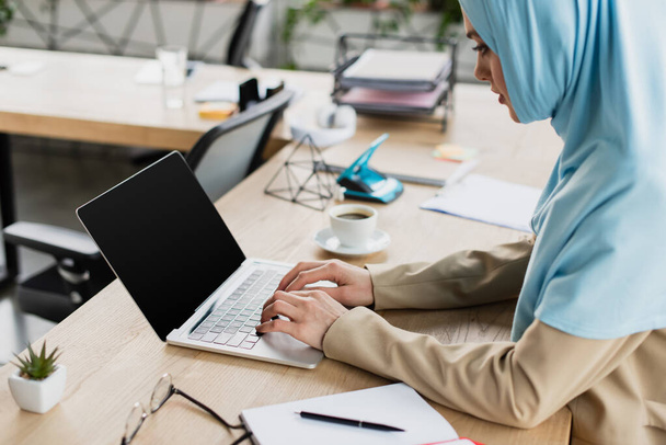 mladá arabská podnikatelka v hidžábu psaní na notebook s prázdnou obrazovkou v kanceláři - Fotografie, Obrázek