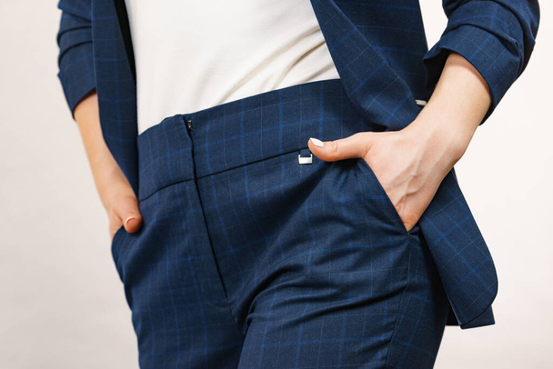 Business woman wearing suit holding hand in pants pocket. Detail view hips in trousers - 写真・画像