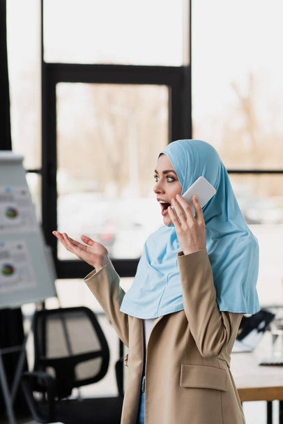 amazed muslim businesswoman gesturing while talking on mobile phone - 写真・画像