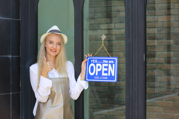 Gyönyörű szőke haj lány áll nyitott bolt tábla lemez ajtóban magabiztosan előtt kávézó. - Fotó, kép
