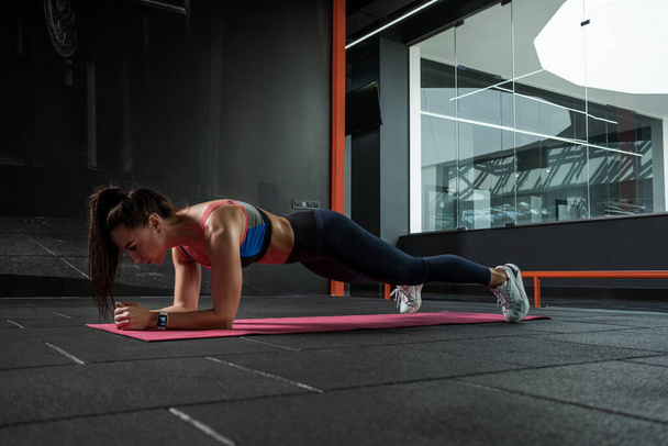 Fit girl doing front elbow plank on mat at gym - Foto, Imagem