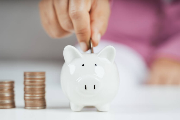 Close up of woman hand putting money coin into piggy bank for saving money. saving money and financial concept - Φωτογραφία, εικόνα