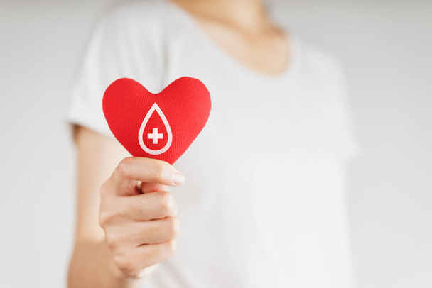 Nainen, jolla on punainen sydän ja verenluovutusmerkki. terveydenhuolto, lääketiede ja verenluovutuskonsepti - Valokuva, kuva