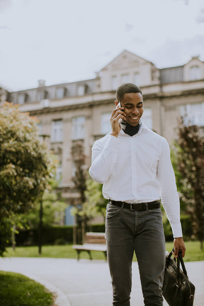 Bonito jovem empresário afro-americano usando um telefone celular em uma rua - Foto, Imagem