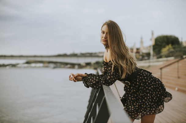 Hezké mladé dlouhé vlasy brunetka žena stojící na břehu řeky - Fotografie, Obrázek