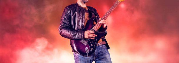 Rockgitarrist spielt Solo auf einer E-Gitarre. Künstler und Musiker treten auf wie Rockstars. Gitarrist steht auf der Bühne.  - Foto, Bild