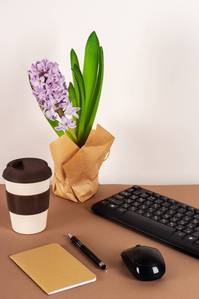 Milieu de travail avec clavier, souris sans fil, ordinateur portable et jacinthe sur fond brun.  - Photo, image