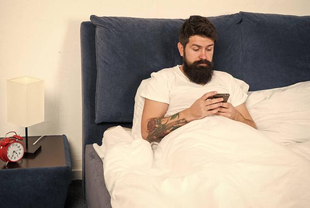 Checking social networks up. Bearded man read sms in bed. Modern life. Modern technology. Internet surfing. Modern conversational experience. Modern live chat allowing real time communication - Foto, Imagen