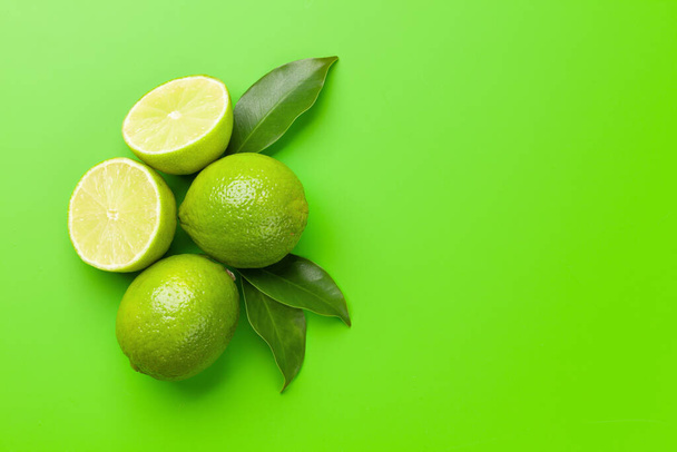 Fresh ripe lime fruits on green background. Top view flat lay with copy space - Valokuva, kuva