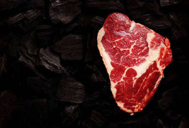 Ribeye steak over hot coal barbecue grill backdrop. Top view flat lay - Foto, imagen