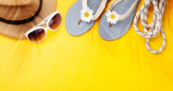 Articles et accessoires de vacances d'été. Tongs, lunettes de soleil et chapeau de soleil sur fond jaune. Vue du dessus plat avec espace de copie - Photo, image