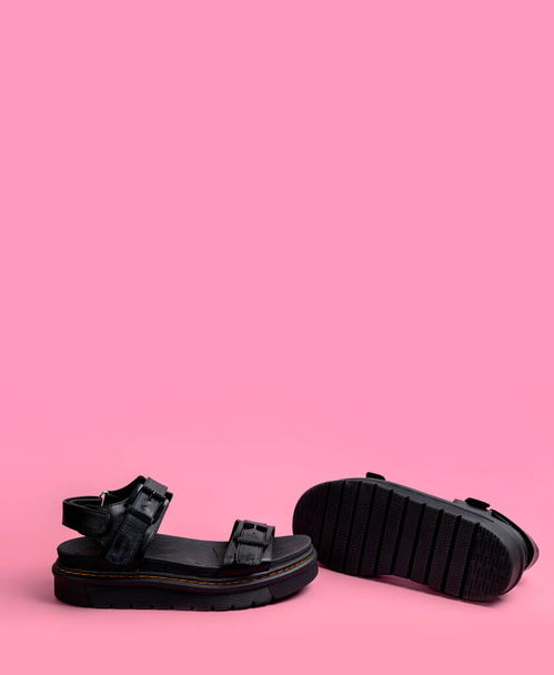 Sandalias de cuero negro para mujer de verano sobre fondo rosa plano laico espacio de copia. Moda casual elegantes zapatos femeninos de moda, sandalias ásperas con suelas gruesas. Concepto minimalista, publicidad de pies. - Foto, Imagen