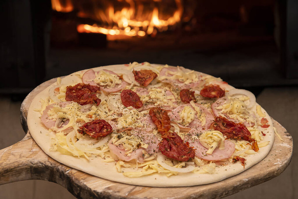 In den Holzofen kommt rohe brasilianische Pizza. Selektiver Fokus - Foto, Bild