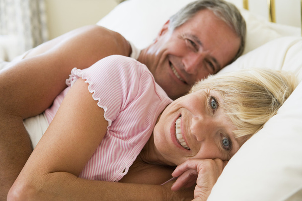 Couple lying in bed smiling - 写真・画像