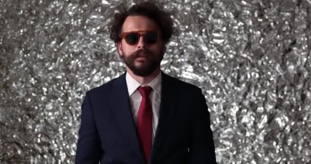 hombre de negocios fresco con un bonito traje con corbata, levantando sus gafas de sol para mirar de cerca algo en una pose de moda - Metraje, vídeo