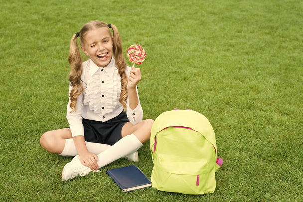 small girl hold book. lollipop for kid. childhood developing. girl with notebook and candy. back to school. kid with school bag. smiling child with backpack. sweet teen youth - Zdjęcie, obraz