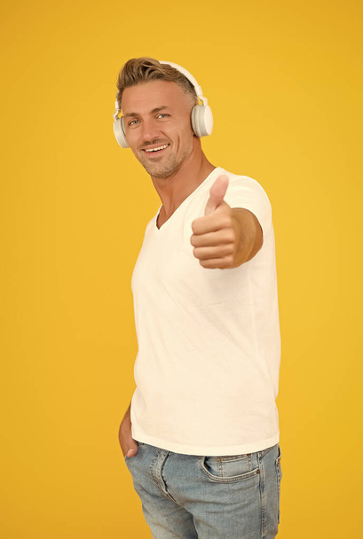 Because your ears deserve the best. Handsome man give thumbs up yellow background. Headphones technology. Approval sign. Listening to music. Modern lifestyle. Approval sale - Фото, зображення