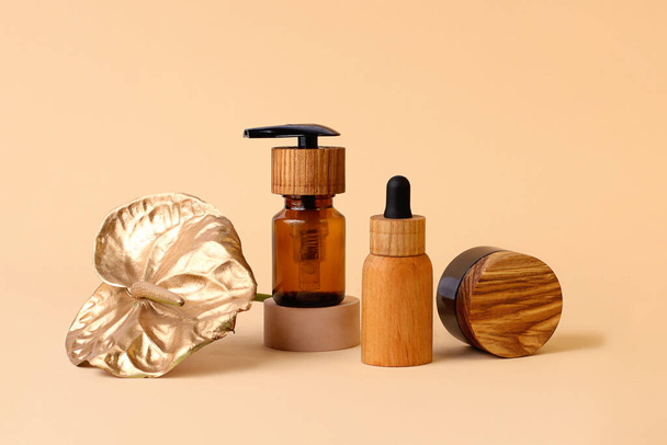 Composition from the wooden cosmetics bottles and golden flamingo flower.Neutral beige colors,zero waste containers.Photography with copy space,good for advertising.Trendy geometrical podiums. - Photo, Image